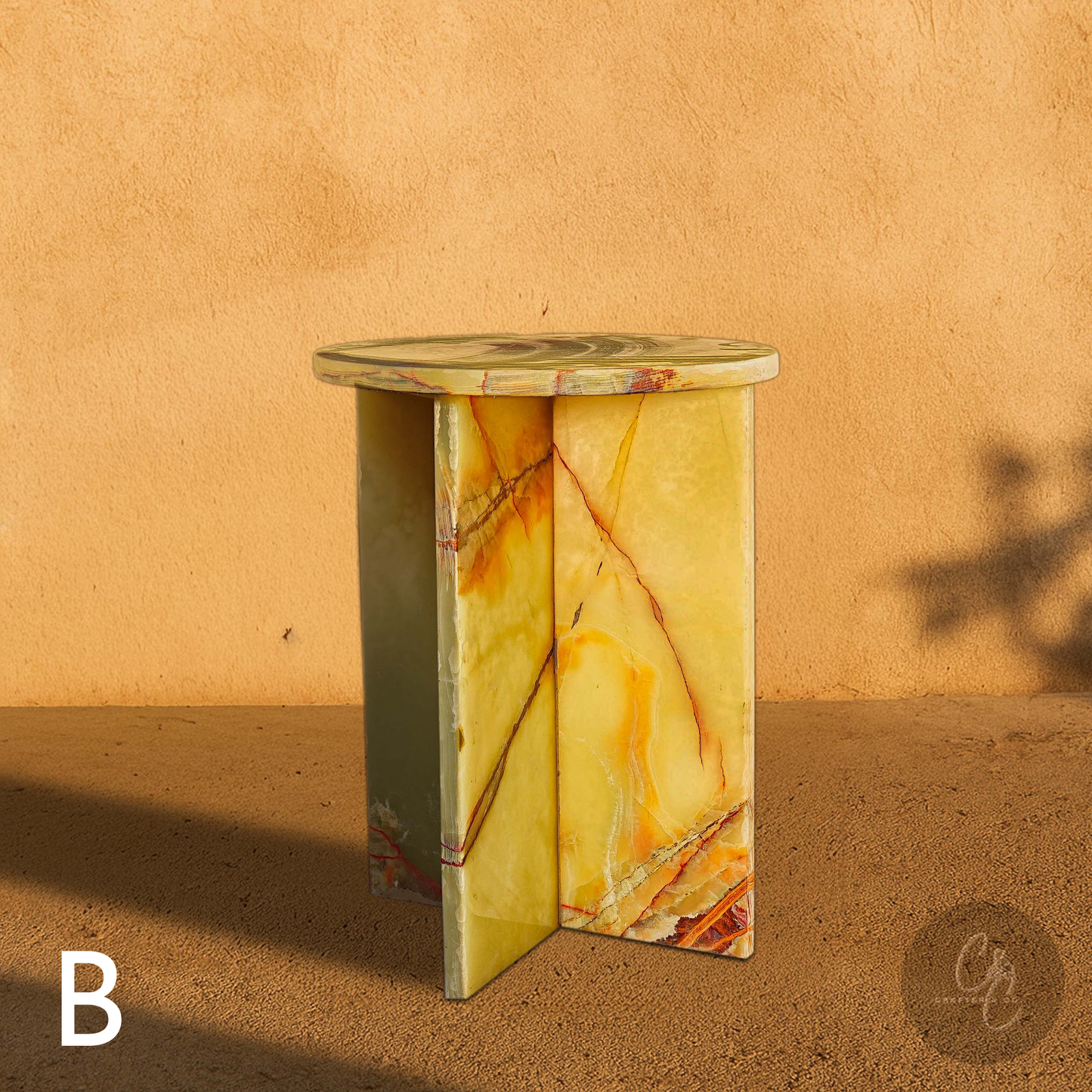 Green Onyx Cross Side Table in front of beige wall.