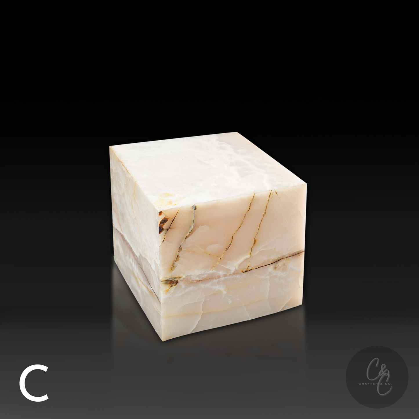 White onyx cube side table variation C shown from the front profile, highlighting its translucent stone and bold golden veining.