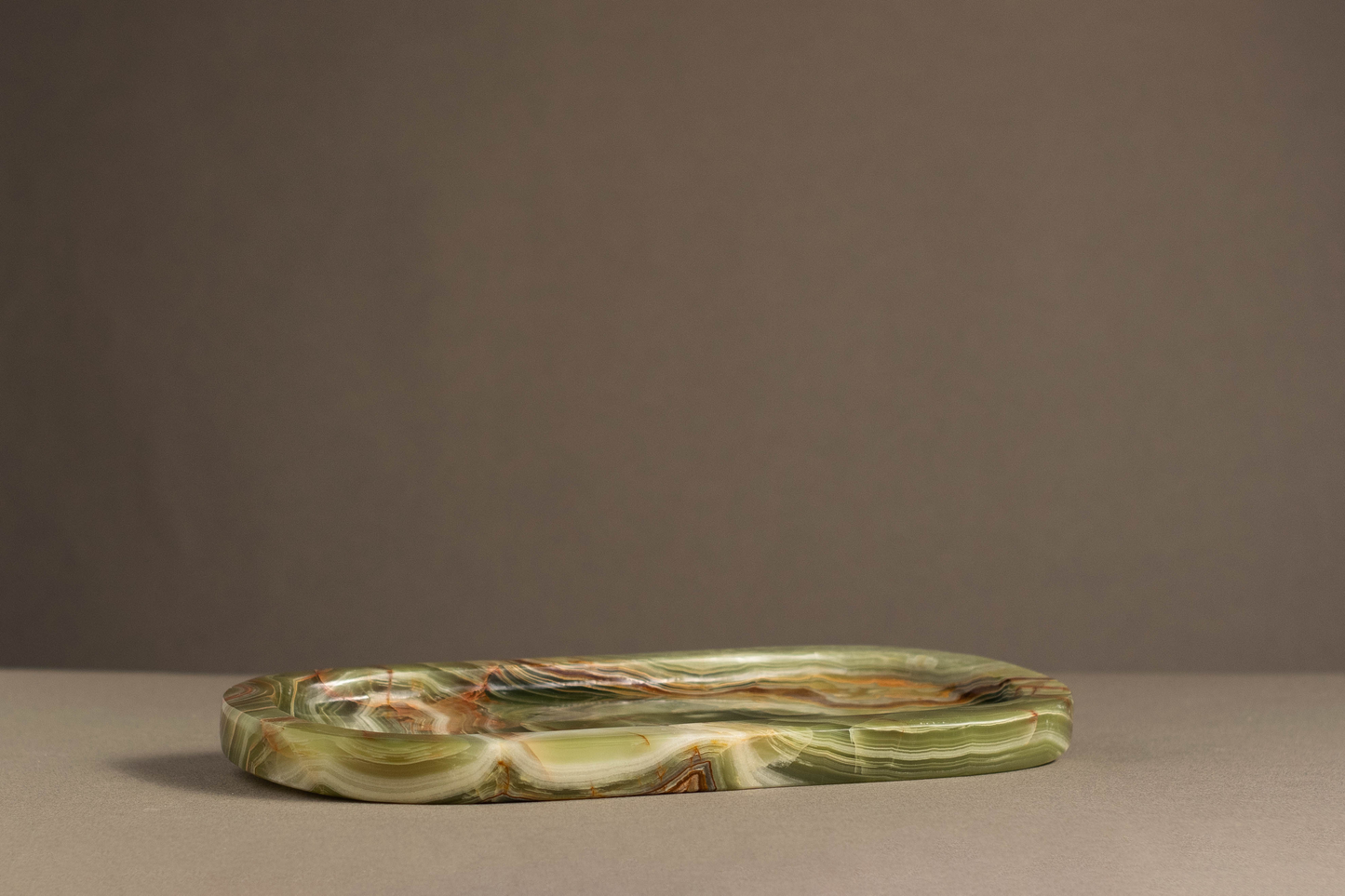 Side view of the Aura Green Onyx Tray highlighting its oval shape and polished finish.