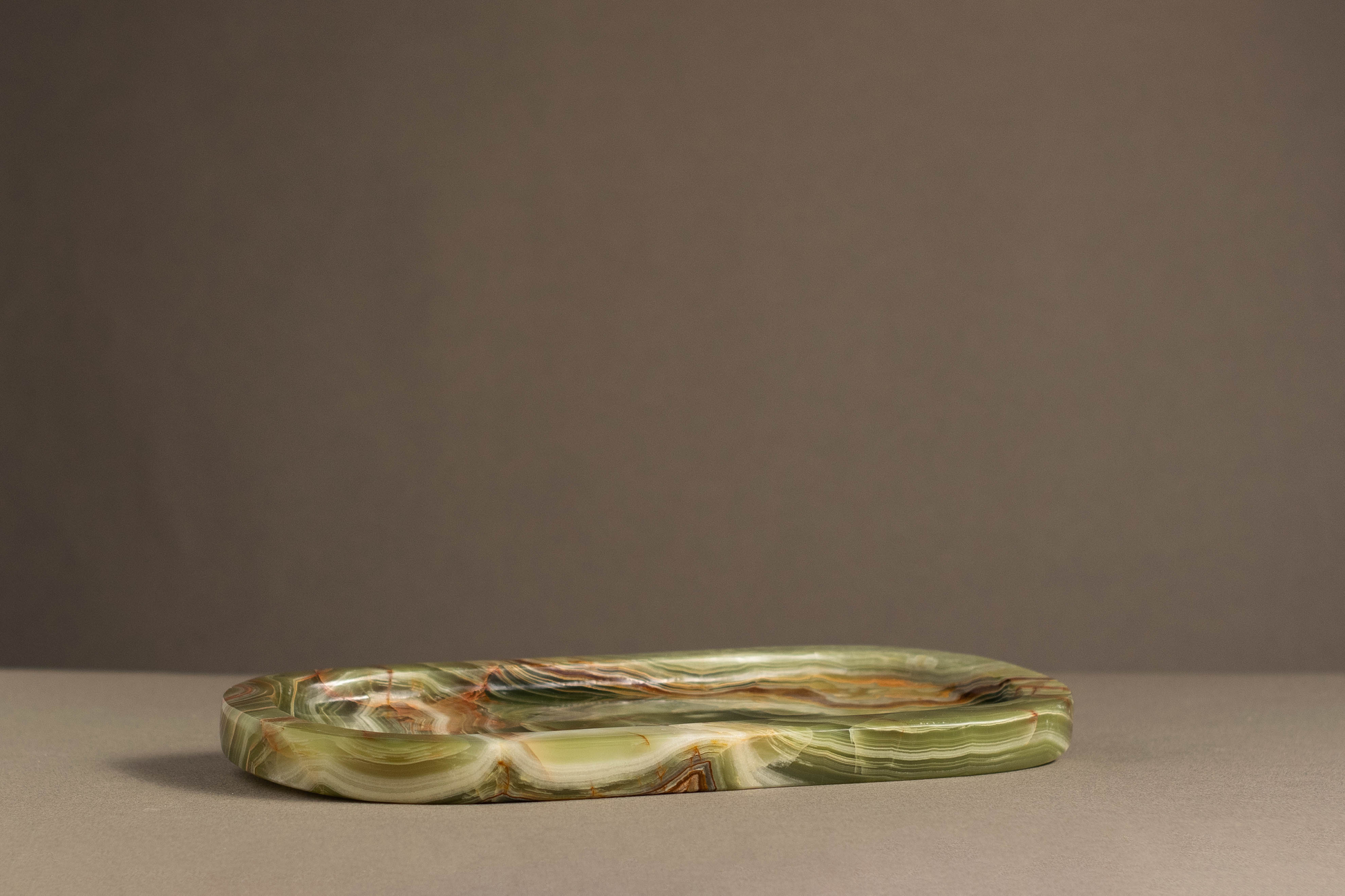 Side view of the Aura Green Onyx Tray highlighting its oval shape and polished finish.
