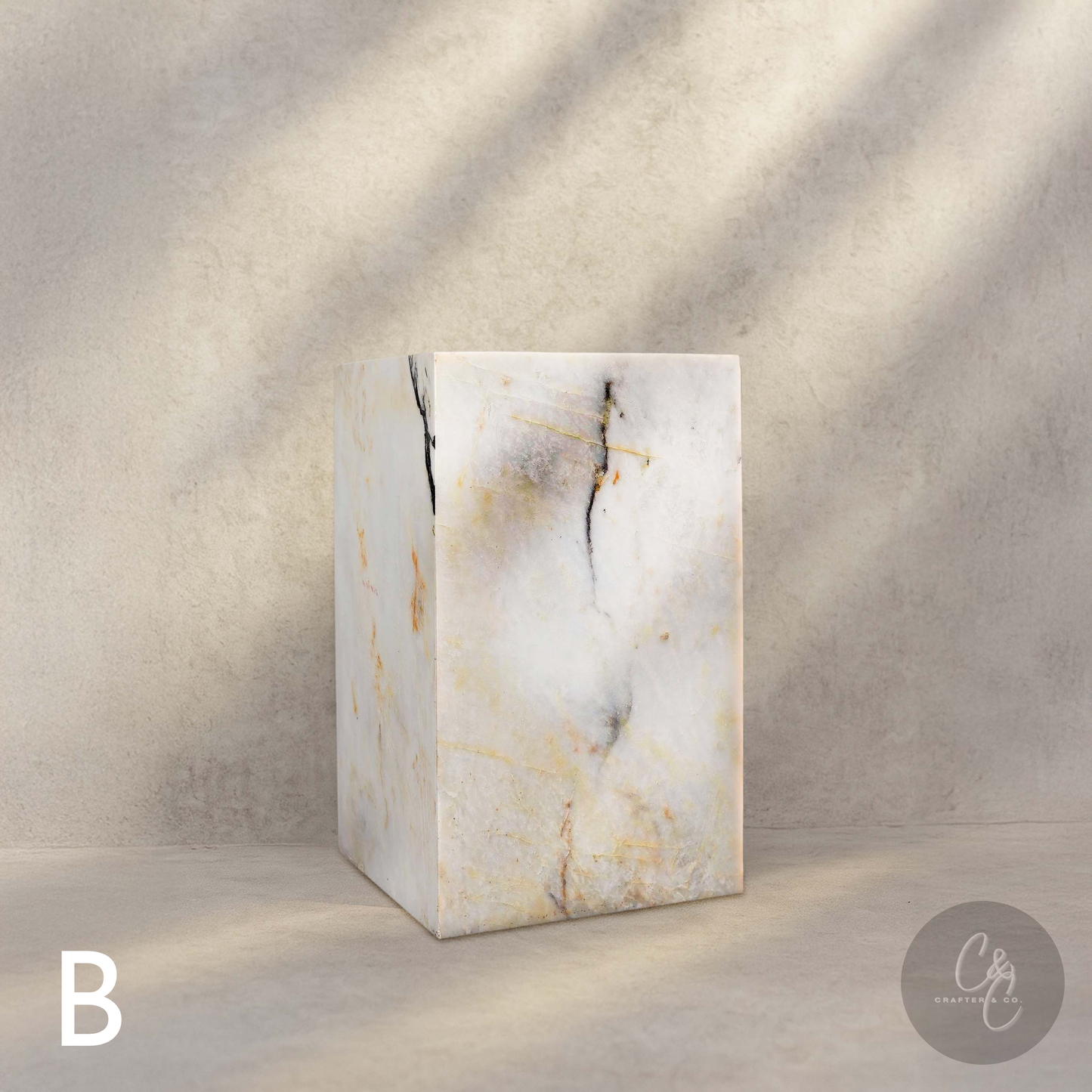 Calacatta Monet marble column side table with bold grey, gold and charcoal veining in a luxury contemporary setting.
