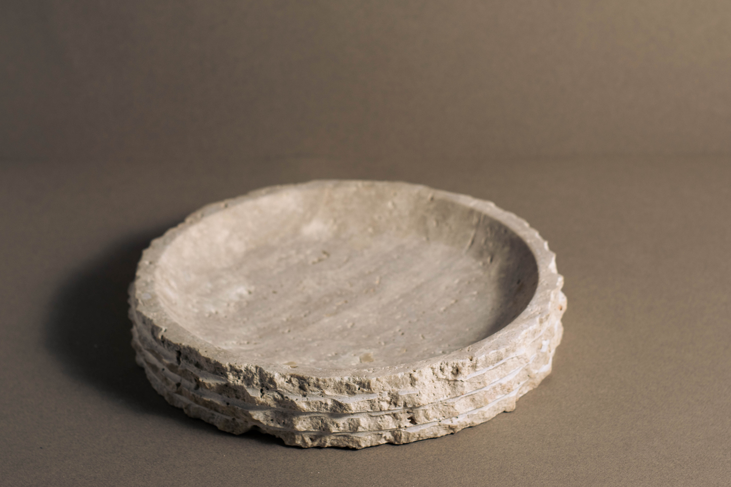 Eclipse Travertine Bowl displayed from a front angle highlighting its sculptural profile and natural stone finish.