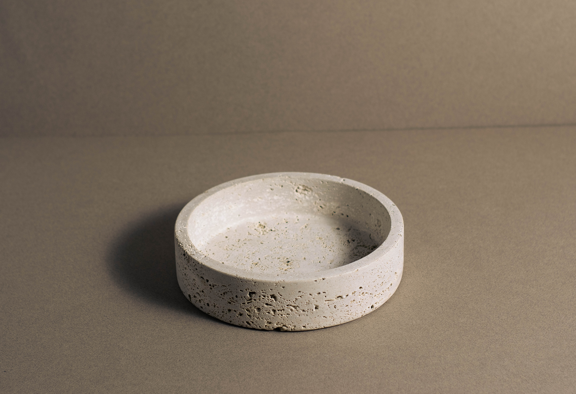Orb Travertine Round Bowl viewed from a front angle showcasing its circular shape and natural stone texture.