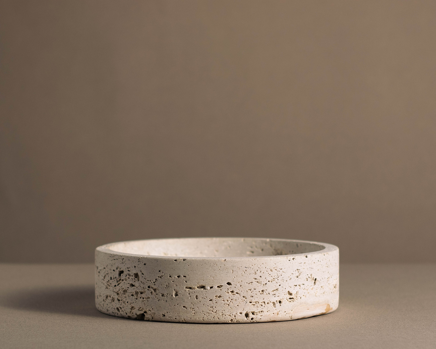 Side view of the Orb Travertine Round Bowl highlighting its handcrafted natural travertine texture and minimalist profile.