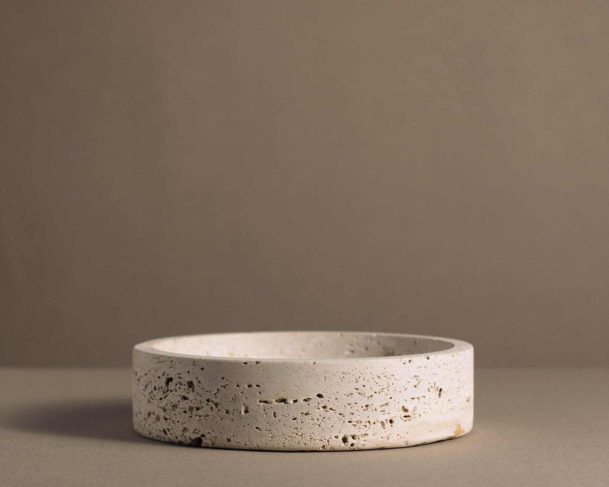 Side view of the Orb Travertine Round Bowl highlighting its handcrafted natural travertine texture and minimalist profile.