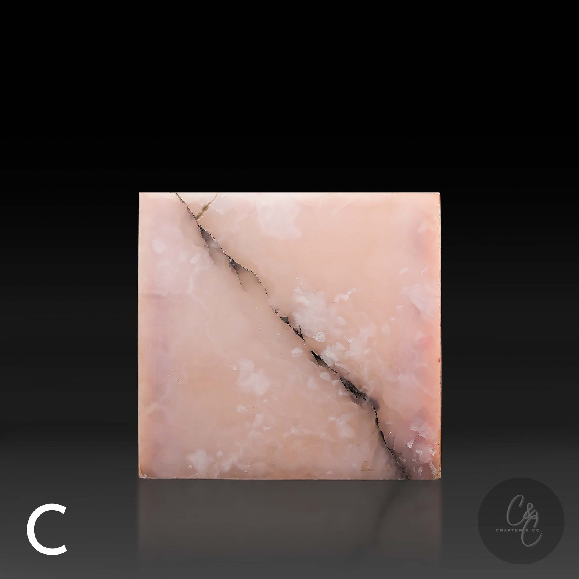 Pink onyx cube side table variation C shown from the front, featuring blush tones and distinctive charcoal veining.