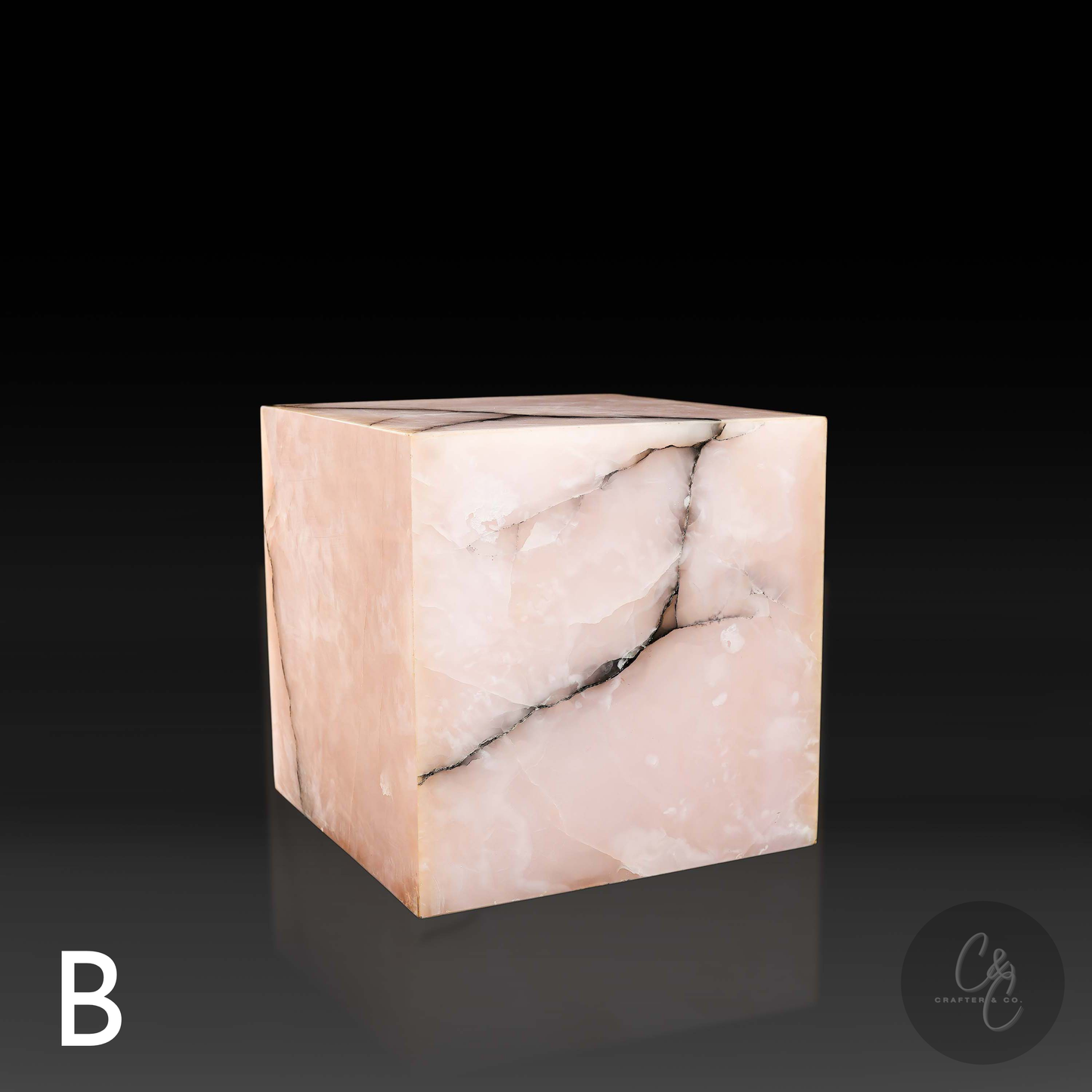 Pink onyx cube side table variation B shown from the front profile, highlighting its blush tones and charcoal veining.