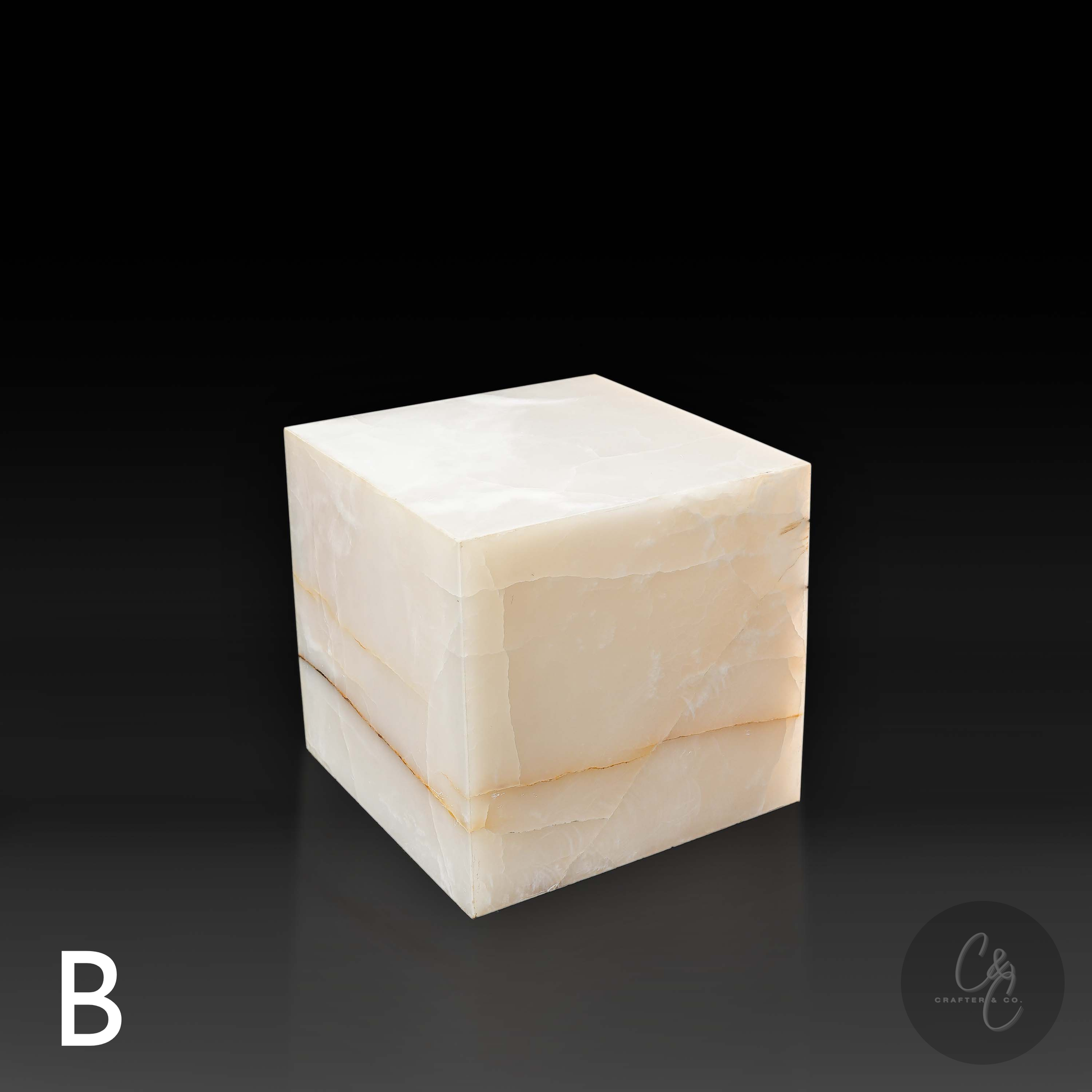 White onyx cube side table variation B shown from the front profile, highlighting its cream tones and natural golden veining.